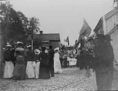 Järnvägsinvigningen och kungabesöket.  Bilden tagen på Storgatan huset till vänster är Ahlstrands hus hör nu till terassen och kyrkparken sedan 1929. Damen i vitt: Fru Zellén maken var läkare i Vimmerby, även regementsläkare. Se gatan med kullersten!   