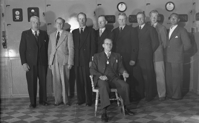 Elverket 1947. ( Ställverket låg i högra delen av Warmbadhuset 
Harry Elg 50 år får samtidigt medalj, uppvaktas av Elverkets personal. Från vänster. 1. Hilding Folkesson, Babbi 2. Maskinist Hilding Pettersson, Pelle på Verket 3. Maskinist Folke Johansson, 4. Stadsmontör Eijnar Larsson, 5. Eldare Erik Carlsson Uggla, 6. Montör Holger Jaensson, 7. Montör Per-Olof Olsson, 8. Bero Pettersson, Billing  9. Sittande maskinist Harry Elg.   
Hilding P, Folke J och Erik C var eldare på Varmbadhuset     
På Elverket laddades bilbatterier                 