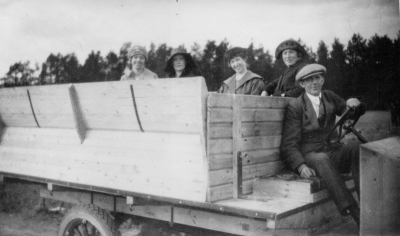 1 st. Ford , vid Ratten Oscar Leander 1. Karin Åberg ( född Lilja ) 2. Nannas syster Gärda 3. Iris Johansson 4. Nanna Lindblom 5. Oscar Leander gummireparatör och trafikbilsägare.  Bröderna Kasks Bilstation, Vimmerby. Förare Gummirep. Oskar Leander Kask. Vimmerby första turistbuss, en mindre lastbil av märket Ford. Bilen användes till vardags för godstransporter men "byggdes" vid behov om för personbefordran genom att 2 st. specialbyggda soffor placerades på flaket. Turistresorna gjordes sommartid på helgdagar och omfattade utflykter till vackra eller i övrigt intressanta trakter i norra länsdelen. Passagerare: Karin Åberg ( född Lilja ) gift med Ossian Åberg Gärda Lindblom, syster till Nanna Iris Johansson Nanna Lindblom. Hade blomsteraffär i källaren på "Ahlströmska huset vid torget.  Gösta Leander   