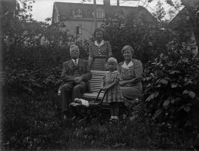 Familjen Karlsson sittande i trädgård.
Från vänster: 1. ? 2. Erin Karlsson 3. Maja med sin dockvagn 4. Ingrid Karlsson
Västra Tullportsgatan