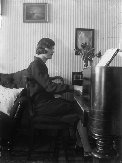 En kvinna som spelar piano. Storgatan 5 Vimmerby, Elsa Blomberg född Hallberg vid taffeln år 1928.