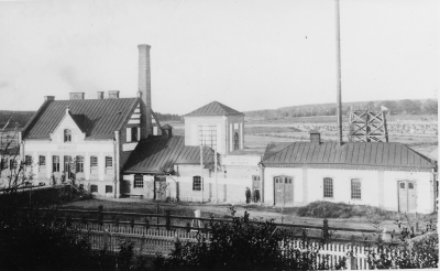 Elverket byggdes i början av seklet, Sevedegatan. Till vänster ,  stadens varmbadhus samt till höger det reservkraftverk staden byggde 1917. Den höga plåtskorstenen var till en panna som  eldades med torv då det visade sig omöjligt att köpa dieselolja för reservaggregatets drift. Från vänster. 1 Hulda Jansson baderska,  2 ?,   3 Hilding Lind,  4 Einar Larsson, stadsmontör.          