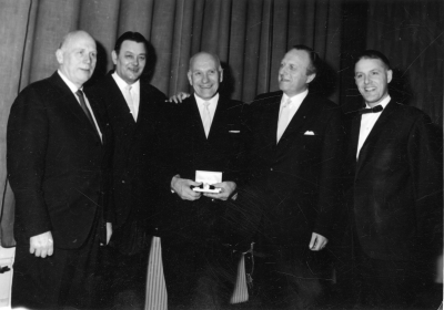 Fr.v. 1. Gunnar Persson Utkörare, 2. Tor Lundgren Drätselkammarens ordförande, 3. Staffan Wettermark Brandförman, 4. Erik Paulsson Lantbrukare S.F.ordförande., 5. Stig Alemyr Riksdagsman.  Wettermark får guldklocka för 35 års tjänst i brandkåren 1966.  