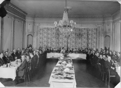 Hantverksföreningen. Raden längst t.v. mot väggen nr 1.  Anders Berg Tobakshandl. 2. Ingemar Karlsson V.T.  4 Verner Sandström, tobakshandlare,  5. Helge Mörfeldt, Järnhandl.  Rad nr 2. ryggen mot kameran nr 1. Per Dunge, 2. Vibeke Dunge, 3. Lennart Wenström,  Presidiét mot gardinväggen längst bort  nr 2 fr.v. Axel Dunge, nr  5. Märta Dunge, 6. Kennemo, bryggmästare. Rad 3 ryggen mot kameran nr 1 närmast kameran Ture Grönqvist, frisör, 2. Kalle Karlsson, klädeshandlare.