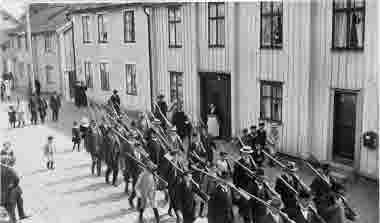 Skyttekåren paraderar på Storgatan.15 Wallin, 19. Ludvig Pålsson, 20. Skomak. Västerberg, 25 Fru Ebba Dahl, 28. Oskar Johanson, 29. Axel Ståhl, fabrikör, 33 Bertil Westman, 38 Fritz Högman ( arbetare hos Ståhls möbler ), 40. Albert Borgstrand, 42. Ture Hammargren,  44. Nilsson, smed, 49 Garvare, Österman.     