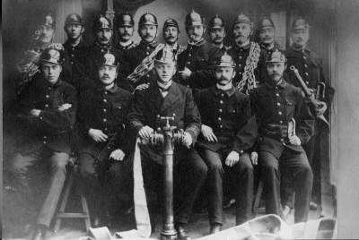 Vimmerby elitbrandkår år 1914. 1. Karl Fransson, Stenarbetare, 2. Josef Wenström, Kopparslagare, 3. K.W. Jönsson, Charkuterist, 4. Carl Otto Andersson, 5. Axel Almer, Plåtslagare, vice Brandchef, 6. Karl Fransson, Virkesmätare, 7. Carl O. Wallin, Skomakare, 8. Gustaf Hultin, Träindustriarbetare, 9. A.L. Thorén, Smed, 10. Napoleon Karlsson, Skomakare,  11. Karl Axel Lindblom, Trädgårdsmästare, 12. Ivar Wettermark, Plåtslagare, 13. Albert Borgstrand, Skomakare, 14. Ludvig Pålson, Guldsmed, Brandchef, 15. Oscar Johansson, Sadelmakare och tapetserare, 16. Oscar Svanberg, Sadelmakare och tapetserare.  