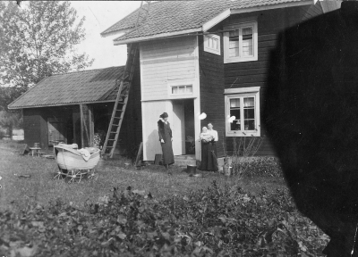 Taget vid Ullvi Leksand den 21 sept 1945 utanför farmors stuga. Mamma Gertrud med lille Eric ? och fröken Sandelius. Taget av ingenjör ?. Till moster Sigrid.