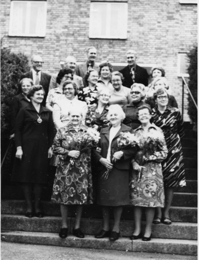 Koperativa Kvinnogillet på fest i Vena Hembygdsgård oktober 1976.  1 Sven Lind, snickare  2 John Andersson, snickare   3 Nils Erik Johansson, rörmontör   4 Göran Magnusson, rörmontör  5 Tora Steiner Fru  6 Birgit Andersson, fru  7 Kerstin Johansson , fru  Ingegärd Månsson, fru  9 Linnéa Jonsson, fru  10 Ruth Larsson, fru  11 Signe [---], fru Sthlm   12 Stina Magnusson, fru  13 Maud Sjöblad, fru  14 Elsie Eriksson, fru  15 Anna Isberg, fru  16 Ella Elg, fru         17 Aina Svensson, fru  18 Anna.Lisa Lind, fru  19 Anna Nilsson, fru. 