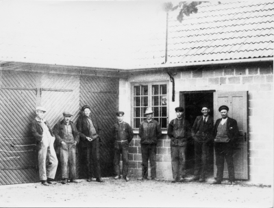 Utanför Oscar Leanders gummiverkstad vid Sevedegatan.   Från  vänster, 1. Kalle Stenberg,  2. Hilding Folkesson, ( "Bobby" ),  3. Maurits Sköldborg, Chaufför ( hos Kask ), 4. Einar Magnusson, Gummireparatör, flyttade sedan till Mariannelund. 5. ?,  6. Gunnar Karlsson, Gummireparatör,   7. Oscar Leander, Gummireparatör, 8 Erik Kask, Åkeriägare.      