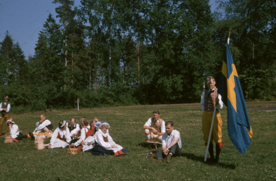 Män kvinnor i folkdräkt svensk flagga fotbollsplan

090506/KG