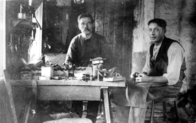 Till vänster: Skomakaremästare Emil Karlsson  ( på fatet ). Till höger: ?   