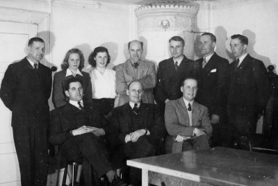 Bakre raden från vänster.  1. Larsson, chaufför. 2. Fru Lindel. 3. Lönngren. 4. Nils Lindström, [---] .5. Gösta Leander, gummireparatör. 6. Valther Lennartsson, intendent. 7. Thorvald Larsson, gummireparatör.  Sittande från vänster  1. Anders Blad, lärare och ordförande i [---]. 2. Folke Nilsson, elektriker. 3. Omar Lennartsson, lärare.     