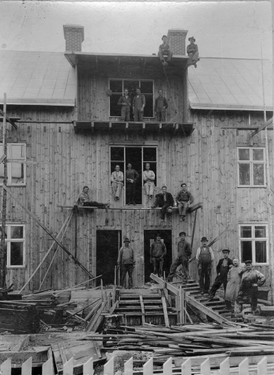 Uppförande av Albin Peterssons nya fastighet Tunaborg vid Storgatan 74, troligen år 1923. Oppifrån. 1,? 2 Ivar Wettermark, Plåtslagare, (Almers), 3, ? 4 Ivar Lindell Tuna?, 5,? 6,? 7,? 8 Arvid Nilsson Alstedt Skomakare, 9,? 10,? 11,? 12 Axel Svensson, Grovarbetare, 13,? 14,? 15 Köhler, Snickare, 16,? 17 Erik Ringholm ? Kakelugnsmakare, 18.?  
T.E.
