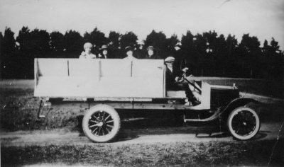 Bröderna Kasks Bilstation, Vimmerby. Förare Gummirep. Oskar Leander Kask. Vimmerby första turistbuss, en mindre lastbil av märket Ford. Bilen användes till vardags för godstransporter men "byggdes" vid behov om för personbefordran genom att 2 st. specialbyggda soffor placerades på flaket. Turistresorna gjordes sommartid på helgdagar och omfattade utflykter till vackra eller i övrigt intressanta trakter i norra länsdelen.   Gösta Leander