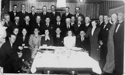 Distriktskogvaktaren vid Skogssällskapet Axel Holm - Jensen fyller år. Kortet taget i Jägarhyddans sammanträdesrum.
Sittande från vänster: Evert Sjökvist banvakt, Ragnhild Sjökvist Everts syster, Hilda Sjökvist mor till Evert och Ragnhild, Bille Holm -  Jensen son till jubilar, Irma Holm - Jensen fru till jubilar, Axel Holm - Jensen jubilar, Ulla Holm - Jensen dotter till jubilar, Karl Oskar Jonsson Gölstugan.
Mittenraden från vänster: Okänd dam, Johan Johansson Gissehult, Karl Gustavsson arrendator på Storebro gård bodde i herrgårdsannexet, Oskar Karlsson Modal, Arvid Nilsson Stora Kasern kommunal förtroendeman, Axel Johansson tog tillnamnet Bottner kommunal förtroendeman son till J. Johansson, Lennart Zakrisson sjöbefäl, Oskar Karlsson Oskarslund, Eskil Johansson fjärdingsman kommunal förtroendeman, ? Högman Skogelund, Okänd, Judit Carlsson Uvekärr, August Carlsson Uvekärr byggnadssnickare arrendator, Alfred Sjökvist banvakt kommunal förtroendeman far till Evert och Ragnhild, Okänd, Okänd.
Övre raden från vänster: Lennart Karlkvist Varpinge senare Modal, Melker Hemmingsson, Edvin Karlsson Gärdehill, Herman Bergström Gärdehill försäljare, Pelle Hellberg, Carl Löfgren Råhäll, Gunnar Karlkvist Herrmosselund.