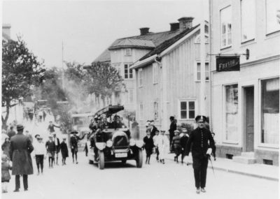Vimmerby brandkår, polis Albert Karlsson. Bilen Tidaholm. Nordgrenska huset till höger i bakgrunden.  Dan Johansson o Stackeruds Frisersalong, huset i mitten ägdes av Isberg. 