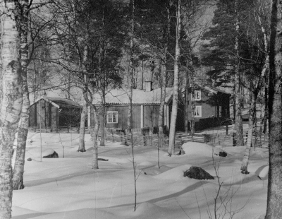 Gästgivarehagen 1940-talet. Östra Tullstugan låg ursrugligen vid Storgatan där nu trappan går upp i kyrkterassen. 1927 flyttades den till Gästgivarhagen och blev den första stuga som uppfördes där. Uthuset till vänster i bild hörde till Klockaregården. Här ser vi den omgärdade gärdesgården som det såg ut på 1940-talet.  