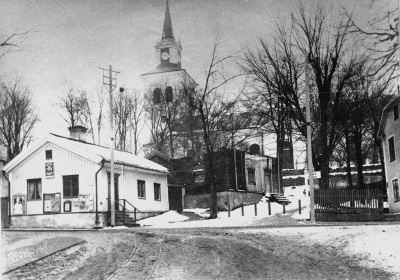 1929 Storgatan före 1929 då husen på Storgatan (vid nuvarande kyrkterassen) inköptes av medel från Reuterska fonden och revs. Skogvaktare Larssons hus överst under rivning. Byggnaden till vänster i Gästgivarehagen.   T.E.
