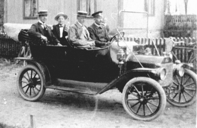 I framsätet Chaufför AK Johansson, Kisa (som blev Kisas första taxichaufför bredvid honom järnarbetare Valfrid Johansson ( Vale ). I baksätet till vänster  Nils Andersson (dragspelsvirtuos) och Adde Hultqvist (bodknodd). Bilen är en Regal Touring som registrerades 22/12 1913, nr E332. Första taxin i Vimmerby. Så här såg den ut, Vimmerbys första taxi. Bilden har sänts till oss från Erik Lindström, Stockholm, som tillbringat sin ungdom i Vimmerby. En vimmerbybo i förskringringen, 73-årige Erik ( Gabel ) Lindström, Stockholm har sänt oss fotot av det här förnämliga åkdonet. Bilden är tagen när den första taxin kom till Vimmerby. Så här skriver Lindström bl a: "Fotot är taget utanför åkare Thunbergs kåk snett emot "Snippen". Jag tror att det var 1910-1911, det var innan jag flyttade till Stockholm 1912 om jag ej missminner mig. Grabbarna som sitter i bilen heter, bak i bilen till vänster dragspelsvirtuosen Niss ansson. Bredvid honom sitter "knodden" i Berggrens speceriaffär,  Adde Hultqvist. I framsätet bredvid taxichauffören, vars namn jag inte kommer ihåg, sitter Valfrid ( Vale ) Johansson, som jobbade hos Beijers Mek Verkstad. Lindström berättar vidare att han själv är vimmerbypojke och att tankarna ofta går hem till gamla "Jemmerby", där han trampat ut barnskorna och som är en bygd som han har kär. Vimmerby Tidning. Notera gärna vklba3851 där AKs broder Ture är chaufför