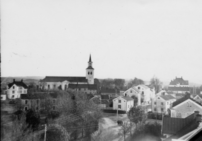 Parti av Vimmerby med gamla klockarebostaden i främre fonden. Taget från Samrealskolan. 

Sekelskiftsbild (nja inte så gammal va?) men Nils Stenberg beskriver läget på 1920-1930-tal.  Huset överst till vänster beboddes av jägmästare Nyman, Nymanska huset. Då bodde också adjunkt Tengström som undervisade på Samrealskolan.
Huset framför i bild beboddes av familjen Lindström, en av sönerna Olle Lindström  dog 2002.   På 1930-1940-talet fanns tandläkare Sune Johansson i Nymanska huset där han  bland annat  var skoltandläkare.
Hitom kyrkan fanns på 1940-talet Evangeliska Fosterlandsstiftelsen missionhus. Skolgård bland småhusen när små - och folkskola fanns på Drottninggatan.
Husen mellan telefontrådarna: 1.Melkerska gården,här vitmålad,  2.Tengvalls fastighet, kontor och bostäder ,fastighetsmäklare,  3.Olle Hagmans son John Hagmans lilla hus på båtsmansbacken, han hade hand om gatusopning,  4. gamla skolan.
Till höger i bild ses missionskyrkan, Nordgrenska huset, handelsbankens tak längst bort.
Uppgiftslämnare: Elsy Nilsson 020425

Dok.090130/SJ