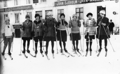 Kortet måste vara taget före1924  Fr v. 1 Margit Sjöholm, 2 Greta Liljedahl, gymnastikdirektör, 3 Svea Strömert, 4 Tyra Bernardina Carlsson, Systembolaget, 5 Pelle Went - modist, 6 Elsa Carlsson senare g m Albin Carlson, 7 Elsa Nilsson, dotter till slaktare Nilsson, 8 Sara Malmberg syster till Karl Malmberg, 9?   T.E.