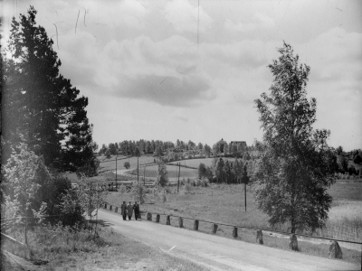 Djursdala kyrka frå norr. Tre personer på väg mot Hallersrum. Fotot taget efter 1939 då kyrkan saknar skorsten. (den togs bort vid restaurering 1939)