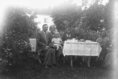 Gruppfoto i trädgård Solhyddan vid V. Tullportsgat. V-by ca 1930. 1 Josef Einar Karlsson "Karlsson på taket" född 1894 22/12 i Flodhult under Tjurstorp, Rumskulla. Föräldrar: 7 Skomakaren Karl August Emil Karlsson och 8 Hilma Josefina Johansson. Karl August Emil född 1869 7/8 i Hult, Rumskulla. Hilma Josefina född 1867 27/7 i Sjöstugan, Holmsjökull, R-la. Ytterligare barn till Karl August Emil och Hilma Josefina, son: Hans Ragnar, född 1898 15/7 i Flodhult, Tjurstorp, dotter: Ern Ingegärd, född 1907 i Marielund, Näs, Rumskulla, Karl Ture Sixten, född 1902 i Marielund, Näs, Rumskulla. Familjen bor i Marielund från ca 1900 - i Lyckås Vimmerby 1910 (Loarpsgat.) - i Solhyddan, Vimmerby 1920 Tullportsgatan.).
