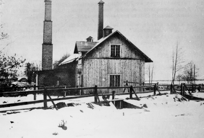 Älåkra kvarn 1905. Sedd från norr Östra Tullportsgatan i förgrunden. Den höga skorstenen på tegelbyggnaden t.v. om gamla kvarnhuset användes för ångning av havre och tillverkning av havregryn i början på 1900-talet. 1875 verkar vara begynnelse på kvarnuppförandet. Lennart Jonsson var den siste mjölnaren.