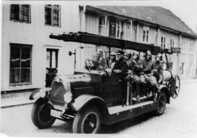 Vimmerby Brandkår Tidaholmsbilen taget på Storgatan. Brandchef Ludvig Pålson i framsätet, vid ratten troligen Einar Pålson. 