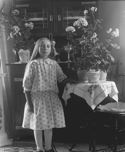 Flicka stående vid blombord.