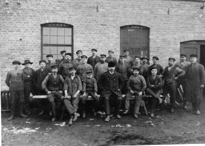 Beijer motorfabrik. Stående från vänster  1. Bengt Evander Svarvare  2. Ivar Bornholm  3. Magnusson Modellsnickare  4. Sköld gjutare  5. Bror Bengtsson gjutare  6. Bengtsson Gjutrensare  7. Simon Magnusson Gjutrensare  8. Pontus Liljeblad Gjutare  9. Carl Gross Filare  10. Edvard Kessel Gjutmästare  11. Valfrid Johansson Hyvlare  12.  Axel Lundberg svarvare  13. Arvid Andersson från Mariannelund  14. Emil Sjögren Filare  15. P. Rehn Gjutrensare  16. Georg Jonsson Verkmästare från Spångenäs  17. Valdemar Lönngren, filare  18. Oskar Berggren svarvare  19. Montör från Katrineholm  20. Nilsson Gjutare  22. Erik Bengtsson Gjutarelärling  23. Nils A. Beijer, Fabrikör  24. Larsson Svarvare  25. Ruben Andersson från Mariannelund                