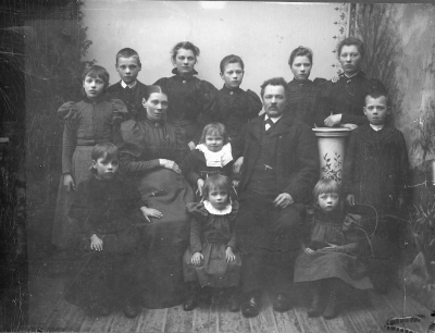 Kort taget 1898.  Oskar ( 1853) o Lovisa ( 1855 ) Lindberg f Carlsson  Barnen: stående fr vänster Ester ( 1885 ), Karl-Oskar ( 1884 ), Olivia ( 1881 ), Alma ( 1879 ), Ida ( 1877 ), Anna ( 1876 )  Sittande fr vänster Signe ( 1889 ), mellan föräldrarna Ingeborg ( 1895 ) Edit ( 1893 ), Jenny I "magen" finns Knut ( 1898 ). Oskar Wilhelm Lindberg slaktare med familj. 1887-1889 Korkatorp, 1891-1901 Hermansborg, Vimmerby. Oskar  Wilhelm (Karlsson) Lindberg född 1853 Målilla Emmenäs. Modern Stina Sofia Andersdotter Emmenäs Målilla        