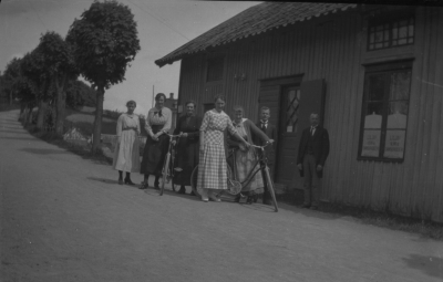 Kyrkogårdsgatan norrut, backen upp mot begravningsplatsen i bakgrunden.
Liljas Herr och Damskrädderi till höger
Handelsträdgården Rosehill (växthus) skymtar till höger i bakgrunden.