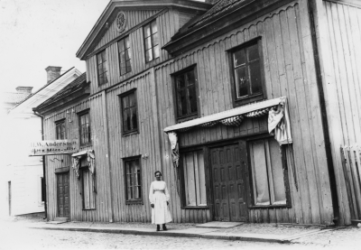Storgatan 23, väster, 1910 -1920. Anderssonska fastigheten. H.W. Andersson köpte det 1878.  På bild, troligen äldsta dottern Signe. Systrarna Andersson överlät firman 1946. Paula Andersson- Johansson, död 1977, gift med Disp. Gustav Johansson. Ny ägare fru Ingrid Karlsson.   T.E.           