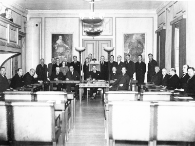 Stadsfullmäktigesammanträde.  Stående från vänster. 1. Emil Larsson 2. Ebbe Ängqvist 3. Bertil Kämpe 4. Fru Fjellander 5. Carl Johansson 6. Valter Hermansson 7. Erik Hallberg 8. Valfrid Carlsson 9. Folke Nilsson 10. Douglas Wistrand 11. Emil Severin 12. Tor Melander 13. Tore Isberg 14. Oscar Leander . Sittande från vänster. 15. Albin Carlsson 16. Teodor Hellström 17. Carl Erland Bentzer 18. Axel Ståhl 19. Ragnar Odevall 20. Simon Andersson, Ordf. 21. Mauritz Malmström 22. Arvid Carlsson 23. Axel Almér 24. Albert Bergstrand 25. Redaktör Carlsson Ragnar 26. Erik Holmberg 27. Sigurd Gustavsson.   