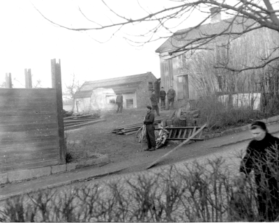 Rivning av husen Storgatan 53-57. Sölls uthus i bakgrunden. Från vänster 1 Hugo Gustavsson, 2?, 3?, 4?.  Dessa tomter lades till Källängsparken. Kalle P på "Lillkampens" gård. T.E.