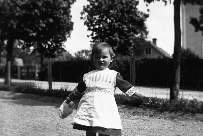 Liten flicka i klänning. Elsa Blomberg Taget på Sollidens gård år 1917.