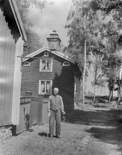 Vaktmästare Karl Svensson, med nyckelknippa.Huset rakt fram flyttat från Drottninggatan 1927, där taxi senare var beläget. Huset tjänstgjorde från början som tullstuga vid norra tullen. Efter tullstuga var huset bostad åt klockaren Melkersson. Döttrarana Melkersson undervisade i piano, ett stycke in på 1920-talet. Även fadern gav pianolektioner. 

Mannen på bild Svensson skötte tillsyn, enligt Torvald Eriksson blev Svenssons dotter ? vaktmästare till 1963.
Östra tullportsstugan flyttades hit 1927. 

Särtryck ur Kalmar Läns museums årsbok för  kulturhistoria och hembygdsvård 1987: Namnet Gästgivarehagen kommer av att hagen i äldre tid var betesmark för gästgivarens hästar, gästgiveriet i Skillingarum.
Under 1800-talet blev hagen en omtyckt festplats.

Cirkeldeltagarna Georg Gustafsson, Kampens gård och Nils Stenberg berättar att  Vif hade fester där på 1920-talet.  Erik Jansson= "Lövet"  kallades  "Fyrtornet"  och "Släpvagnen" var Melker Johansson, han hade skomakeri 
bakom Halldéns bokhandel numera Rosins pappershandel och  Helge Ringholm sålde dansbiljetter ,3 st.ycken för 25 öre.
Kaffet kokades utomhus uppe på berget på en stor sten med lite resta stenar runtom, Anna Holm och Selma Persson skötte eldning och kaffekitteln.
Dansbanan var rund och låg ungefär där husen nu är belägna, mellan berget och vägen.
Uppgiftslämnare: Cirkel Eken/genom Elsy Nilsson, Vimmerby 021003

Dok.090203/SJ