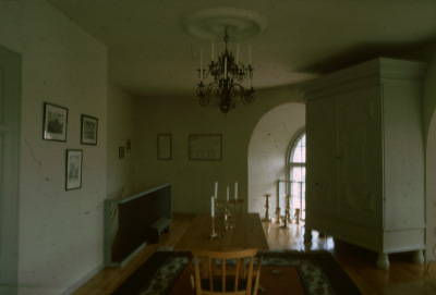 Interiör läktaren V-by kyrka? Stort skåp ljuskrona bord stolar tavlor ljusstakar matta

090421/KG